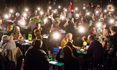 A room with many numbered tables where two people talk at a time.